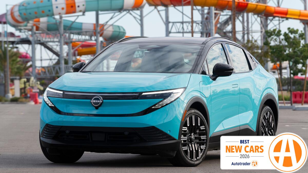 Nissan Leaf parked in front of a rollercoaster.