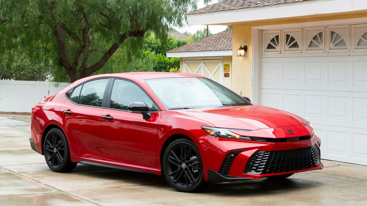 2026 Toyota Camry in red parked in front of a driveway.