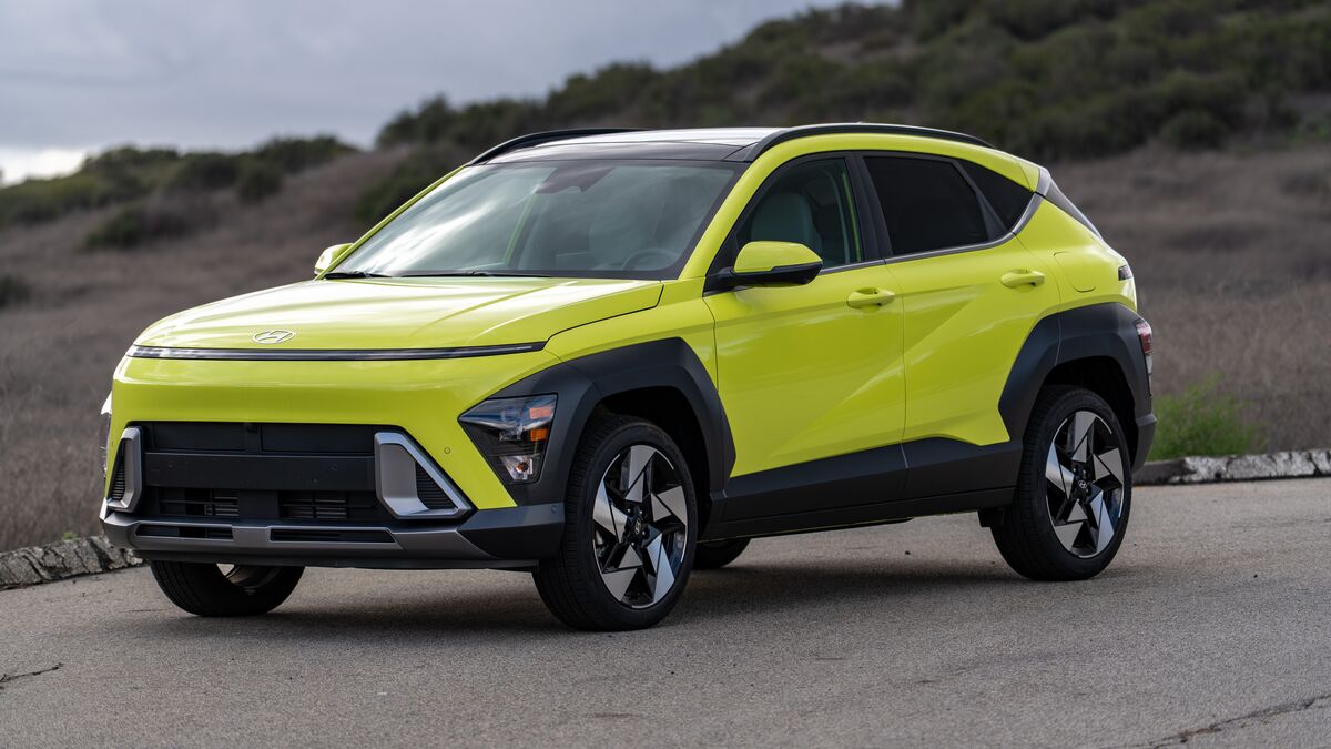 A left-side front 3/4 view of the Hyundai Kona hybrid against a grassy hillside on a cloudy day