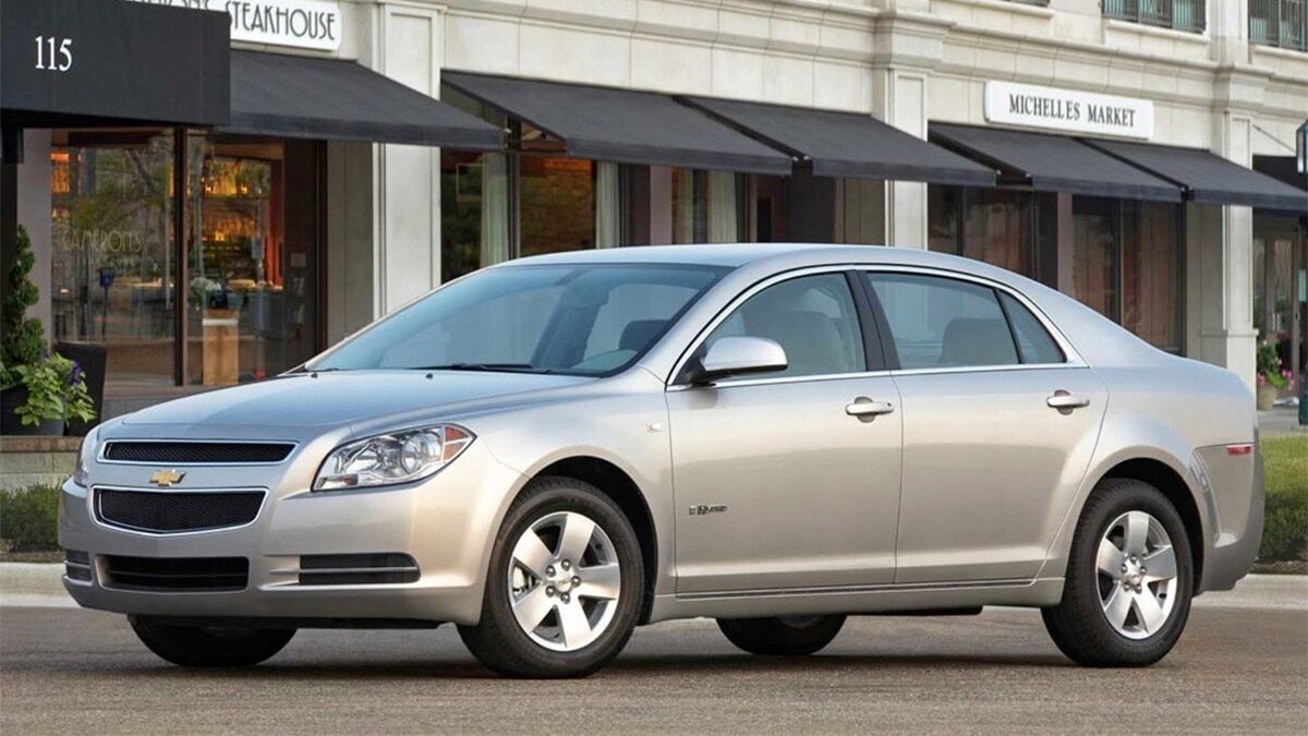2008 Chevrolet Malibu parked in front of shops and restaurants.