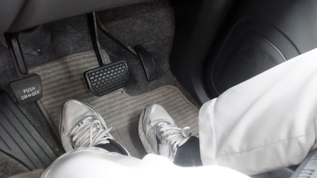 A driver's feet near accelerator and brake pedals.