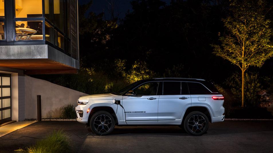 2022 Jeep Grand Cherokee 4xe Summit in white charging at a house.