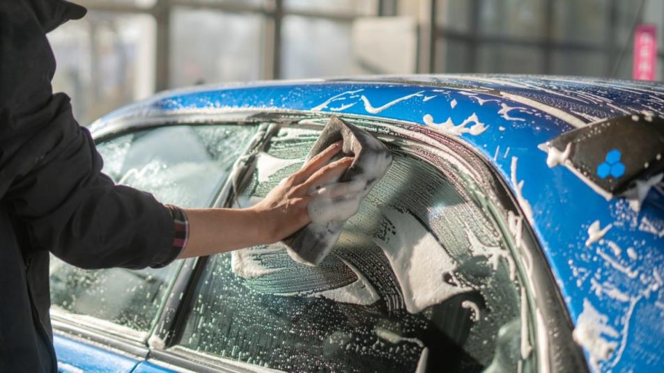 Person washing car with sponge