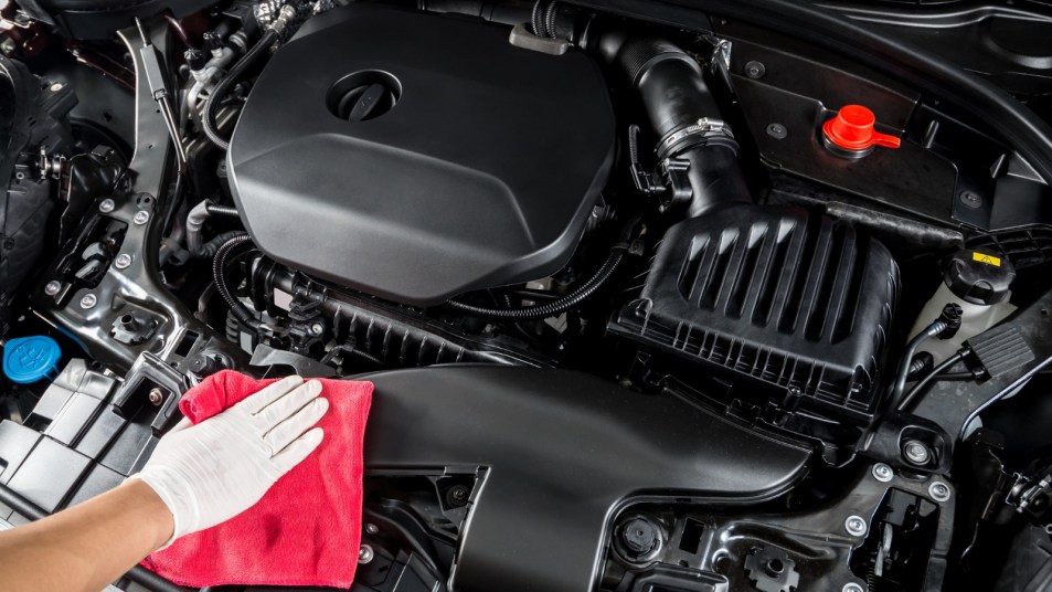 Person cleaning car engine with a rag