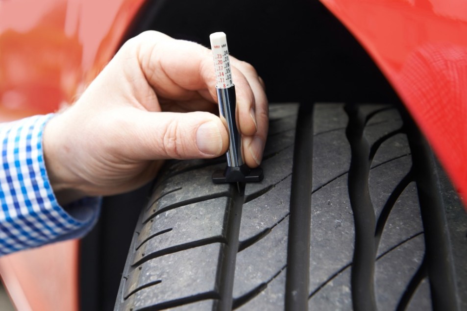 Person using gauge to check tire tread