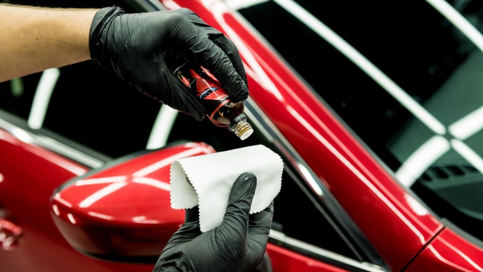 Technician applying coating to car paint.
