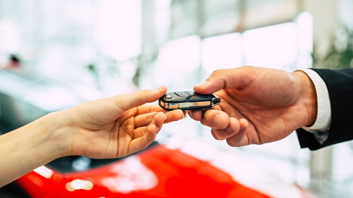 Customer handing key fob to car dealer.