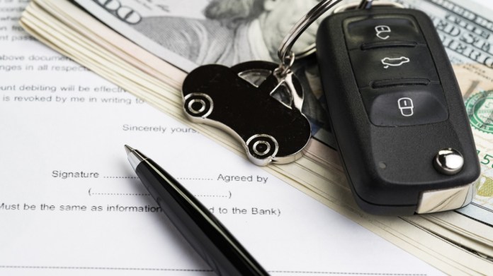 Car keychain and cash on top of a sale document