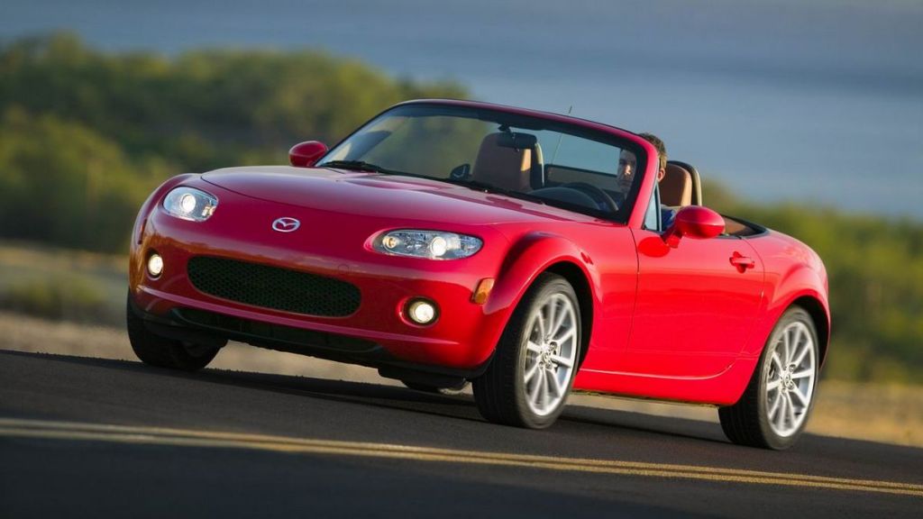 2008 Mazda MX-5 Miata in red driving down a highway.