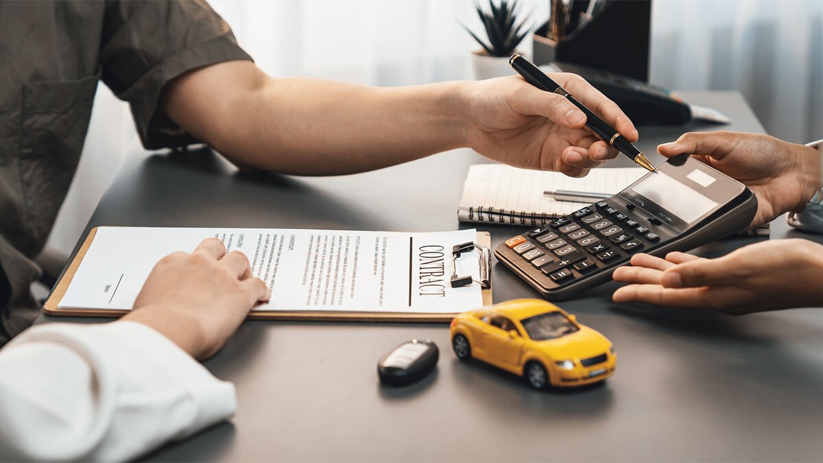 Car dealer calculate interest rate and costs of car loan with calculator, explaining details to customer on term and agreement in dealership office.