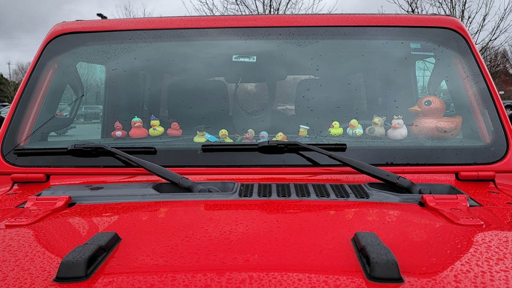 Rubber ducks on dashboard of red Jeep.
