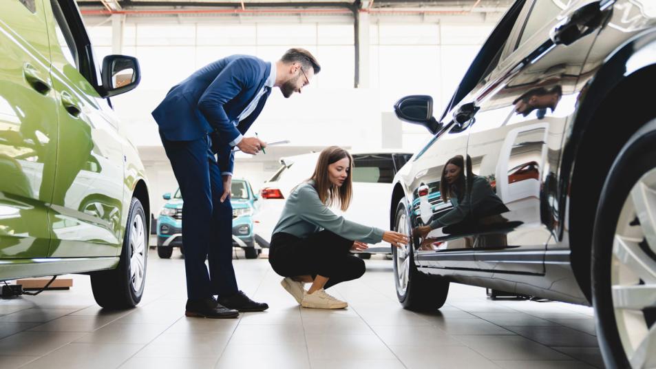 Best time to buy a car with woman looking at vehicle.
