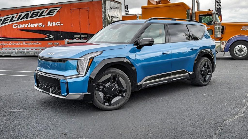 2024 Kia EV9 GT line parked outside in front of a truck.